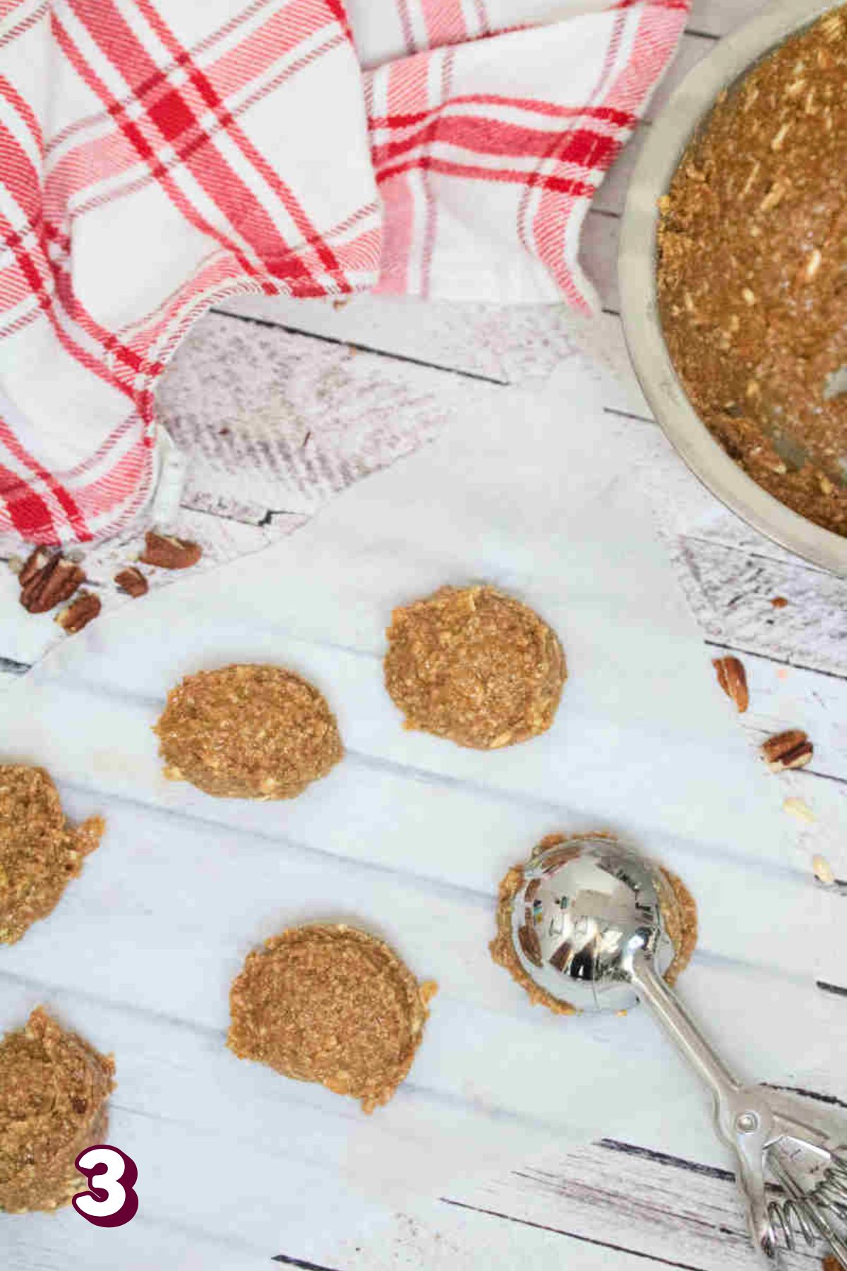 No bake cinnamon balls being portioned with a trigger ice cream scoop onto parchment paper in a line.
