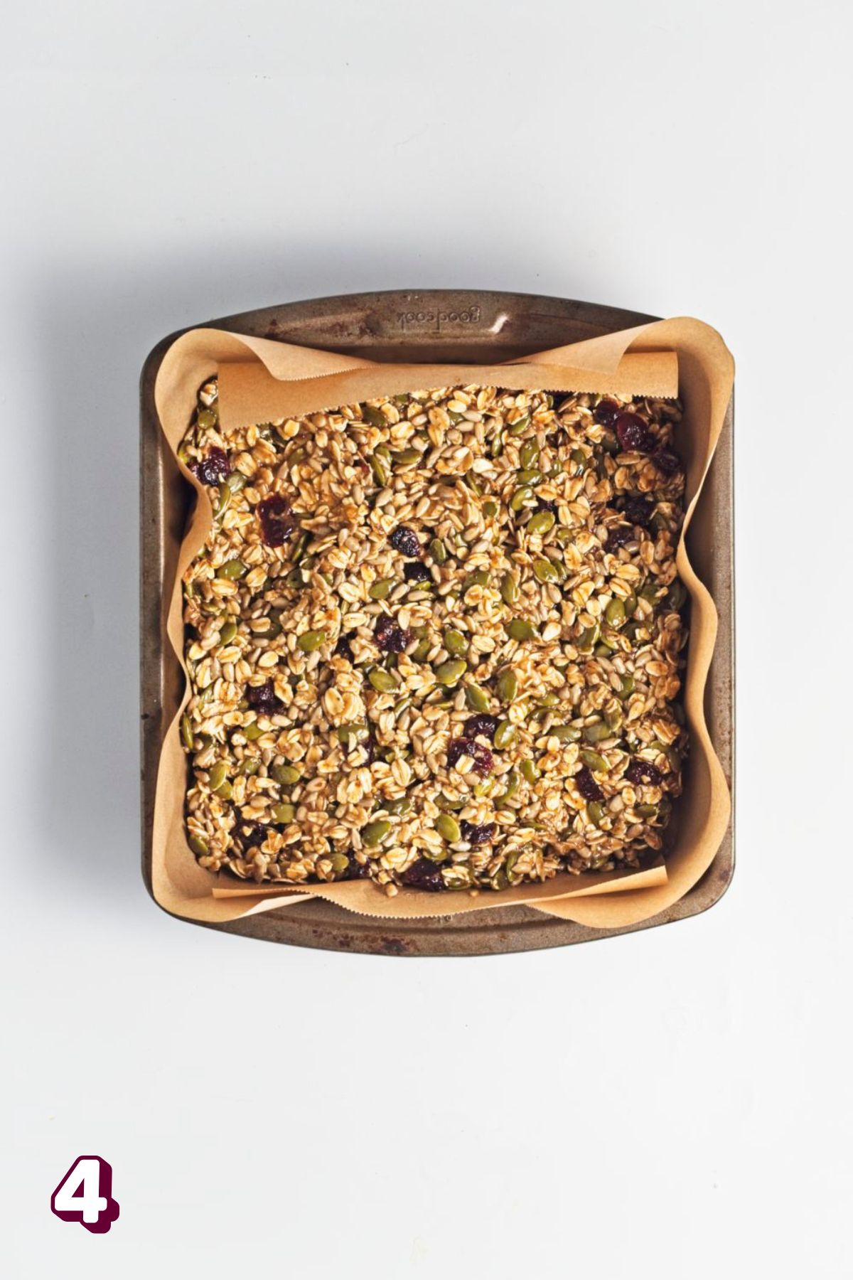 No bake granola bars pressed into a baking pan with brown parchment paper.