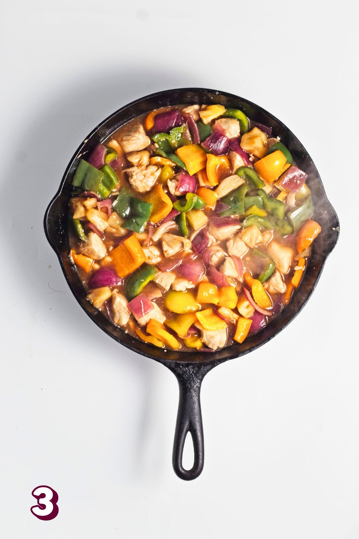 Pineapple chicken dinner with bell peppers in a cast iron pan.