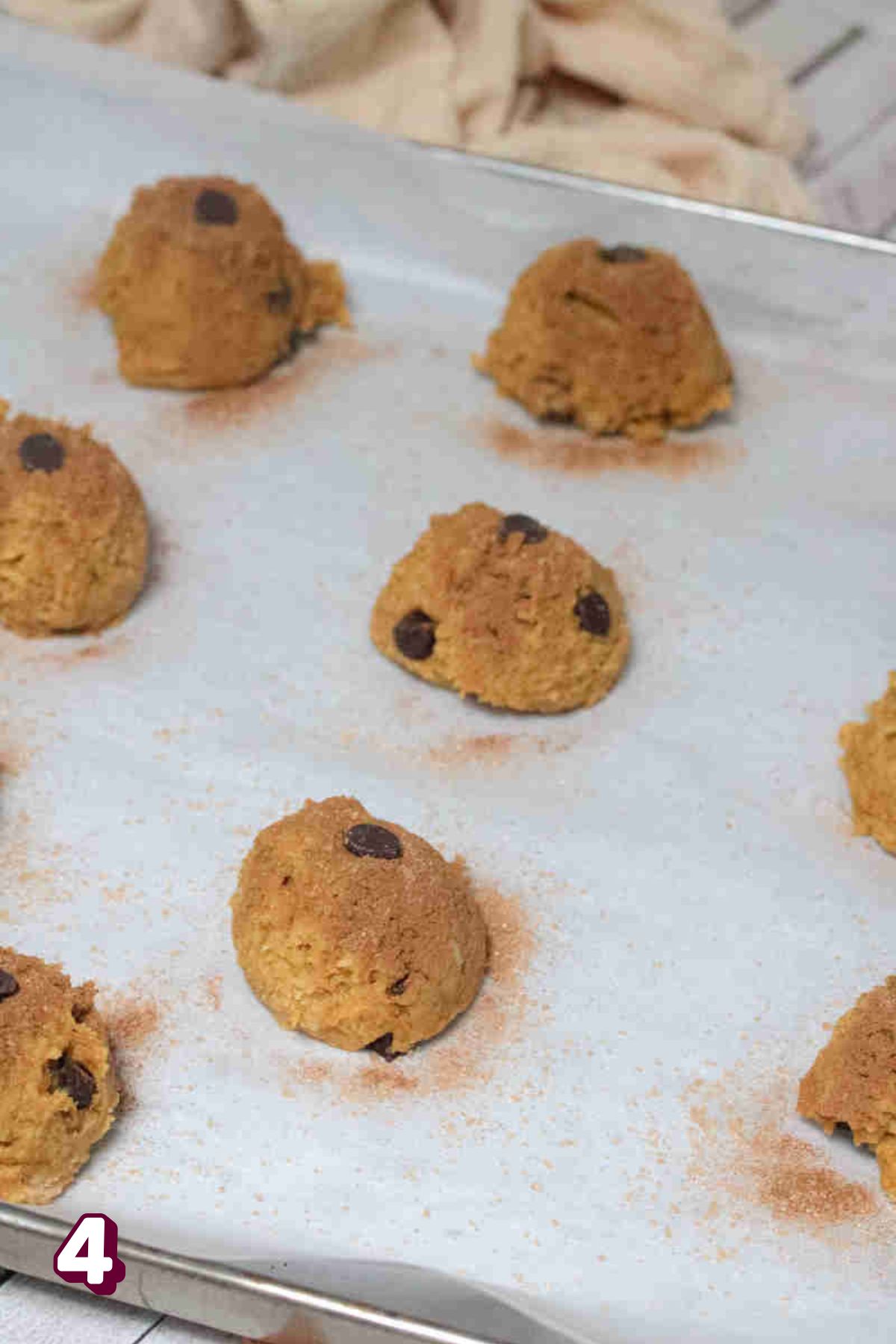 Raw pumpkin chocolate chip cookie batter being portioned onto a lined baking sheet.