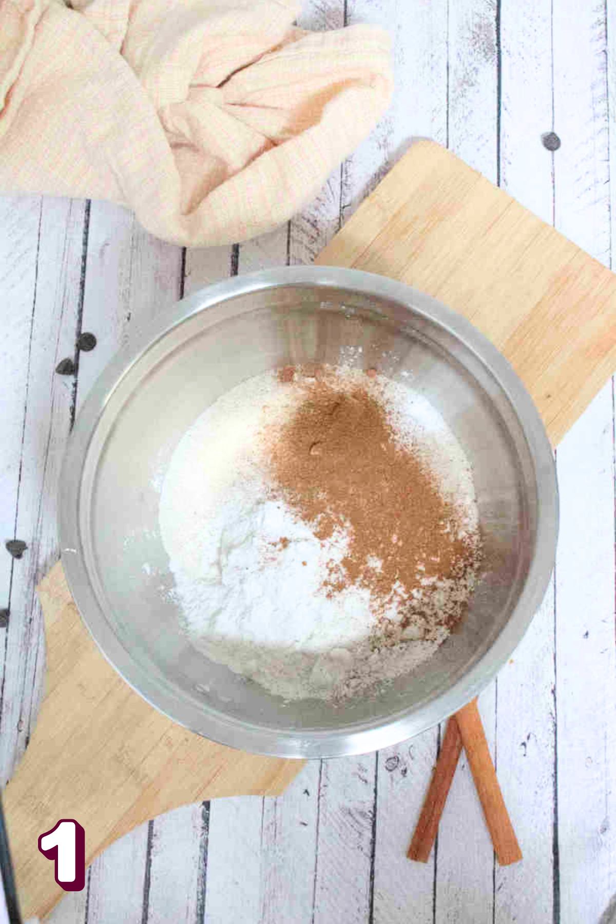 Flour, pumpkin spice, and sugar in a steel bowl on a cutting board.