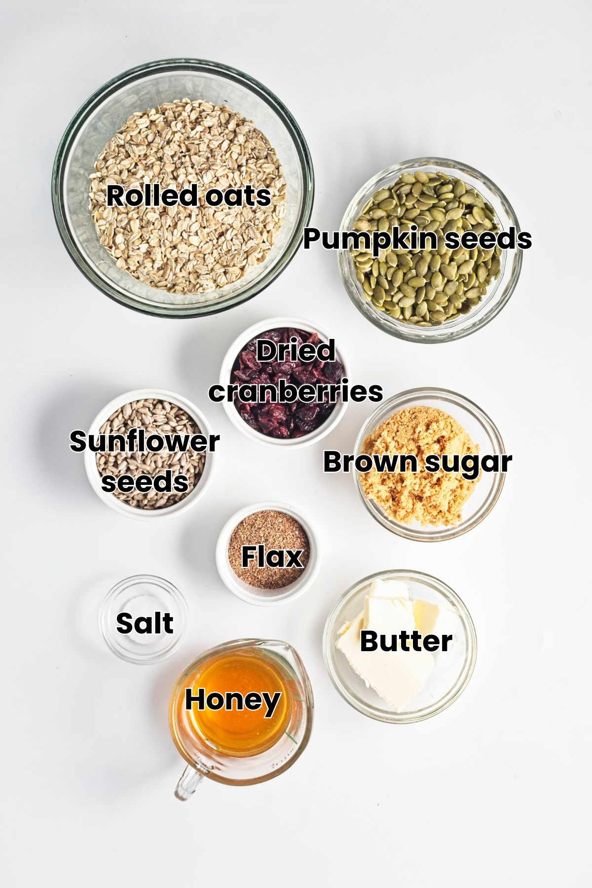 Multiple ingredients like brown sugar, seeds, oats, and honey in glass jars with text labels over top.