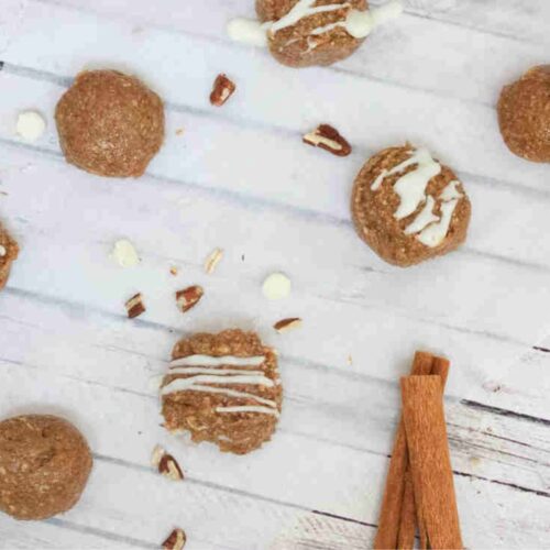 No bake cinnamon roll balls with white chocolate on top on parchment paper.