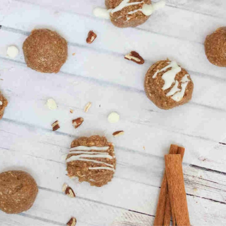 No bake cinnamon roll balls with white chocolate on top on parchment paper.