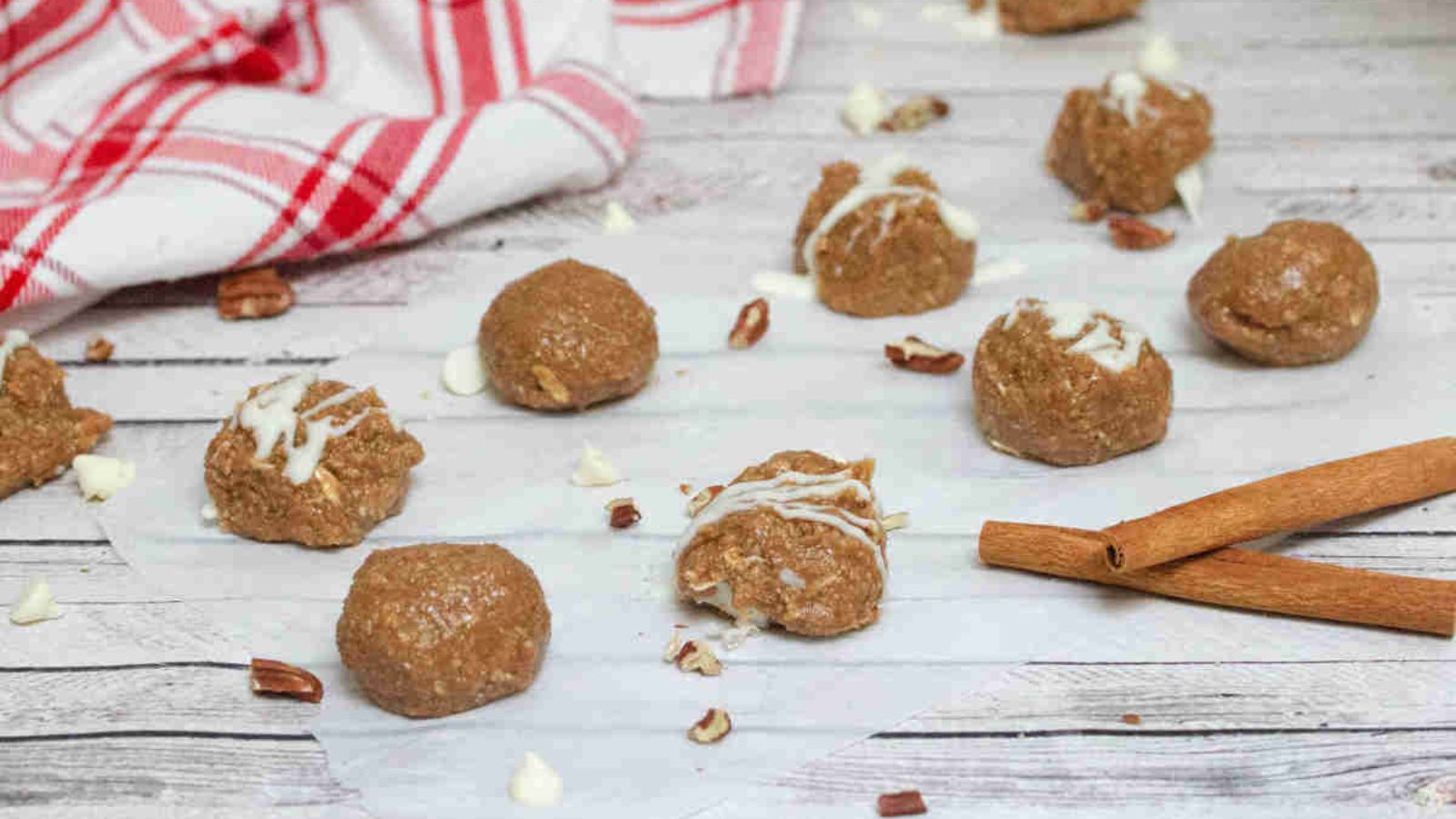 No bake cinnamon roll balls with white chocolate on top on parchment paper.