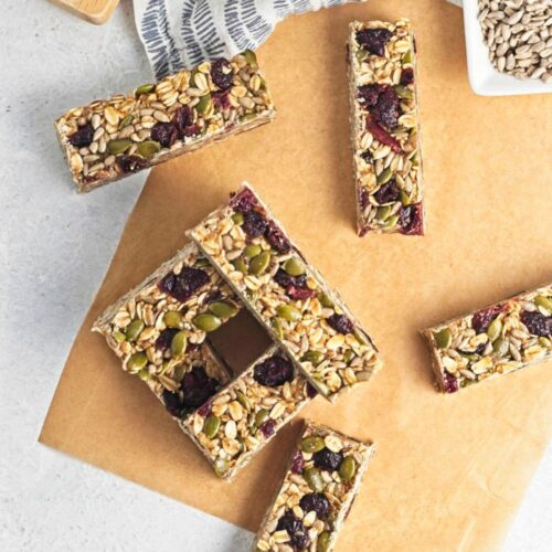 No bake granola bars stacked on parchment paper.