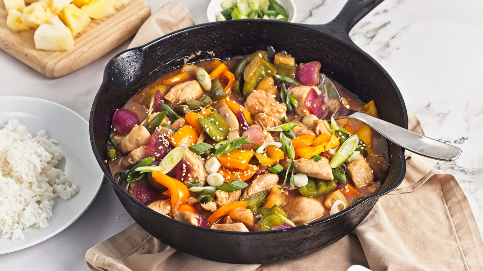 Pineapple chicken dinner with bell peppers in a cast iron pan.