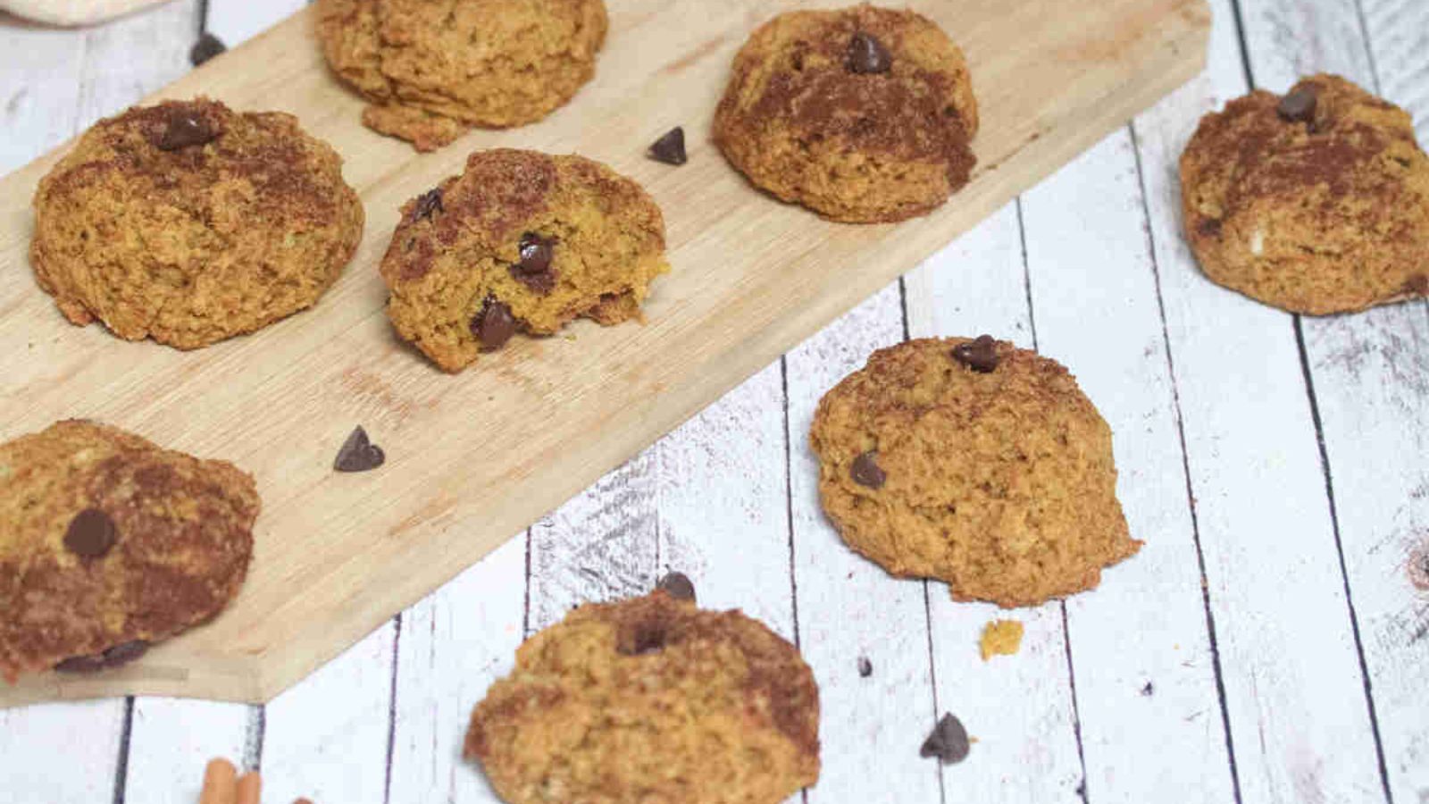 Pumpkin chocolate chip cookies on a cutting board and around them.