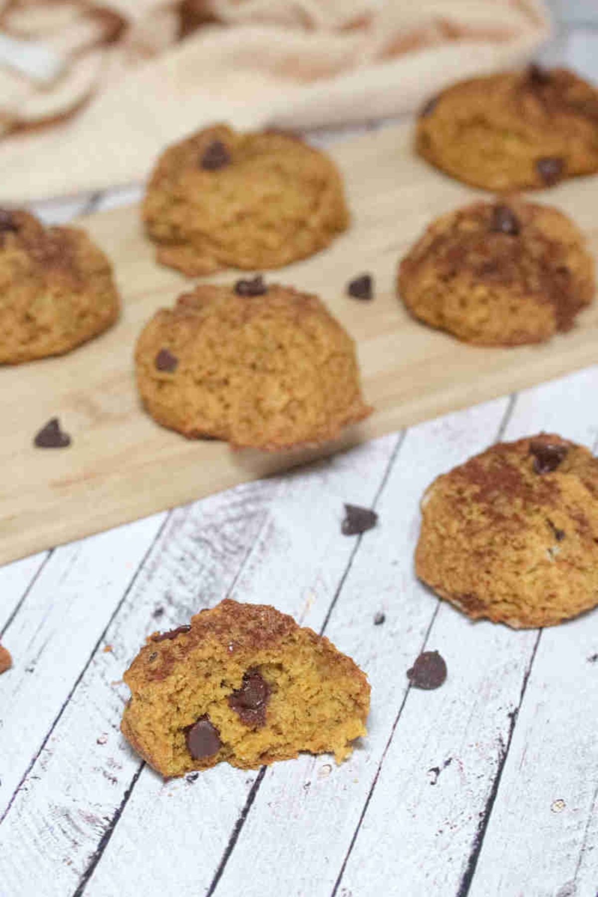 Pumpkin chocolate chip cookies on a cutting board and around them.