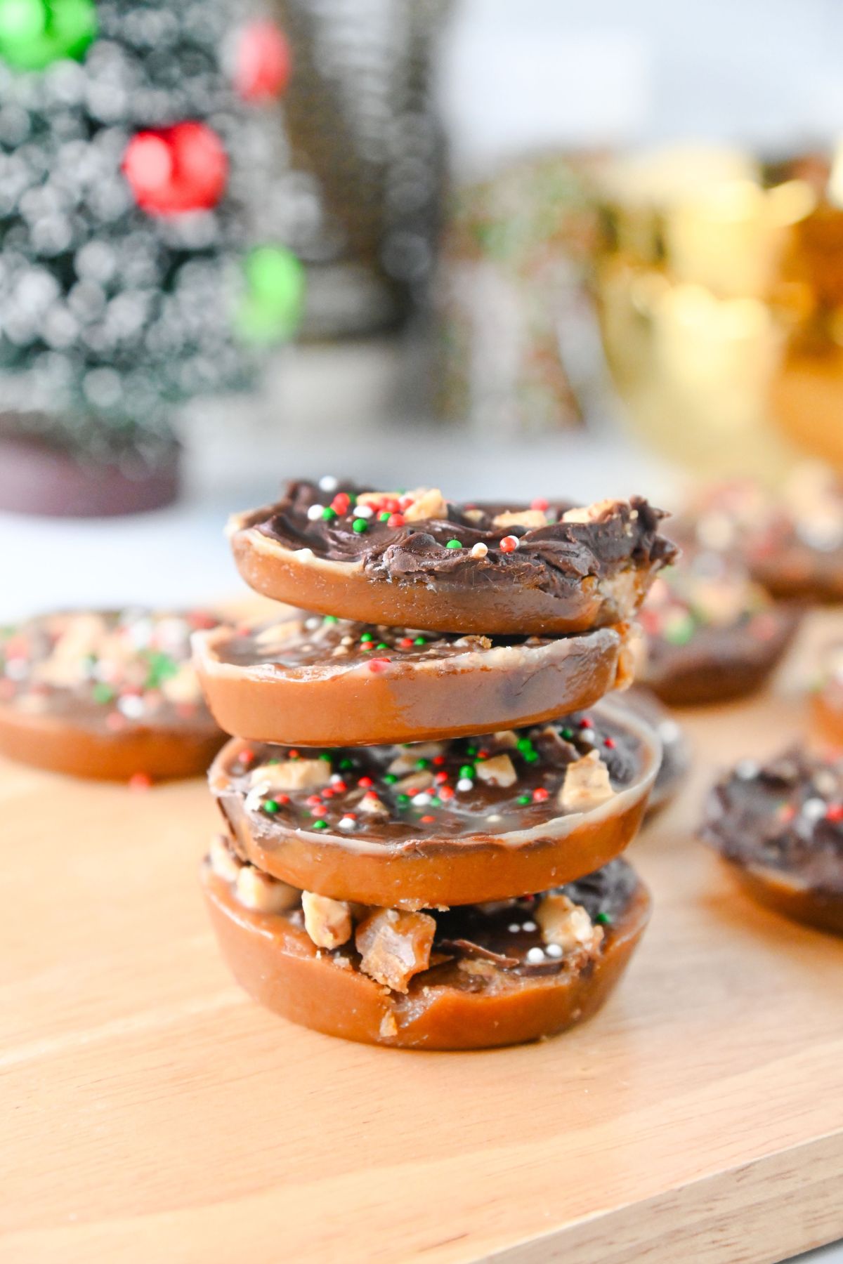 Multiple Christmas crack cookies topped with chocolate, toffee, and sprinkles and stacked on top of one another.